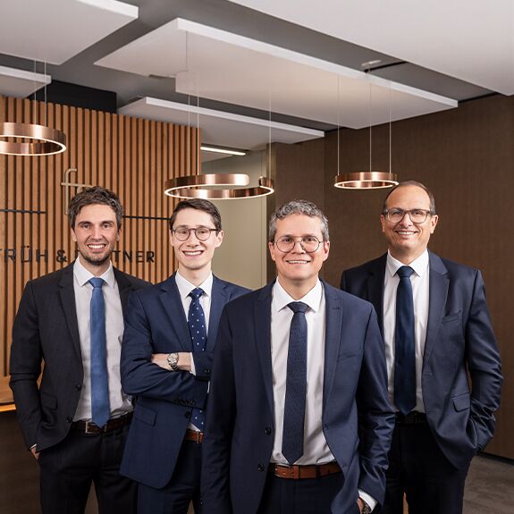 Das Bild zeigt vier Geschäftsmänner die nebeneinander stehen. Es sind zu sehen (von links): Ivo Raissakis (CIO, Partner), Nic Ritter (Geschäftsführer), Harald Wild (Geschäftsführer, Partner), Ralph Früh (Vorsitzender der Geschäftsleitung, Partner)